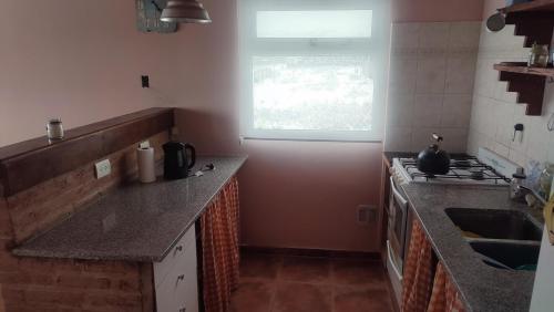 a kitchen with granite counter tops and a window at Mil5inco Al Lago in El Calafate