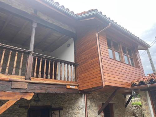 a house with a wooden balcony on top of it at Apartamentos caravia, cachucho-casa in Duesos