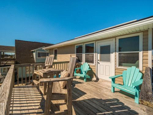 two chairs and a table on a deck with a house at Little Bird in Surf City