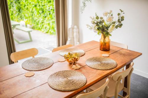een houten tafel met vier hoeden en een vaas met bloemen bij Superb 90m2 Apartment with Garden in Eindhoven