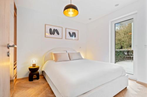a white bedroom with a white bed and a window at Elegant Comfort Modern Apartment in Limpertsberg in Luxembourg