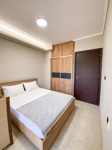 a bedroom with a large bed and a wooden door at Olive Garden by Golden Host in Nea Moudania