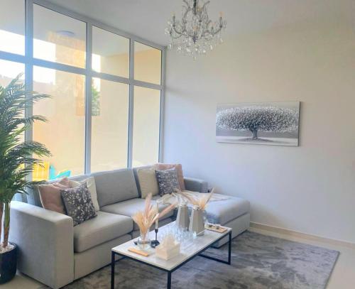 ein Wohnzimmer mit einem Sofa und einem Tisch in der Unterkunft Damac Hills 2 Retreat- Tranquil Luxe, Beyond City with waterpark in Dubai