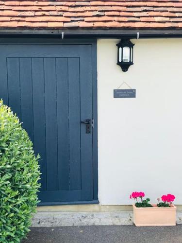 a garage with a blue door and two plants at Winters Farm Cottage in Mayfield