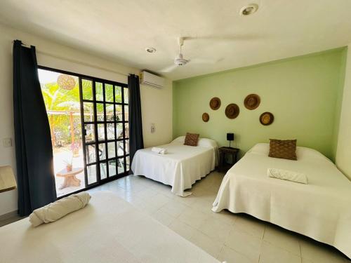 a room with two beds and a large window at Sirenas Caribbean Rooms Holbox in Holbox Island
