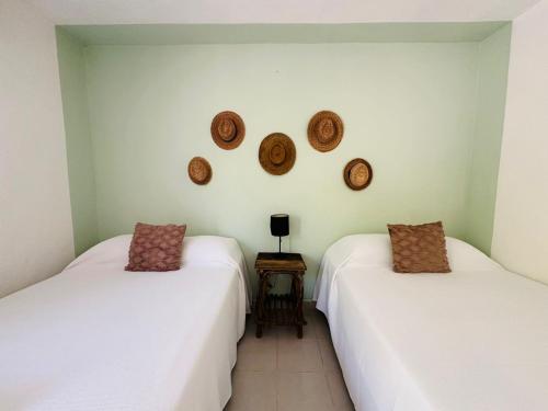 two beds in a room with hats on the wall at Sirenas Caribbean Rooms Holbox in Holbox Island