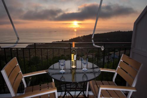 a table with wine glasses on a balcony with a sunset at Elena Studios in Athanion
