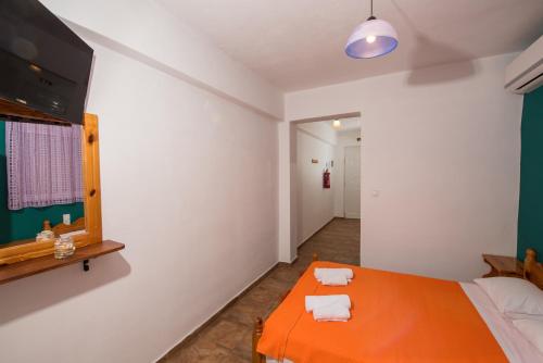 a bedroom with an orange bed and a mirror at Elena Studios in Athanion