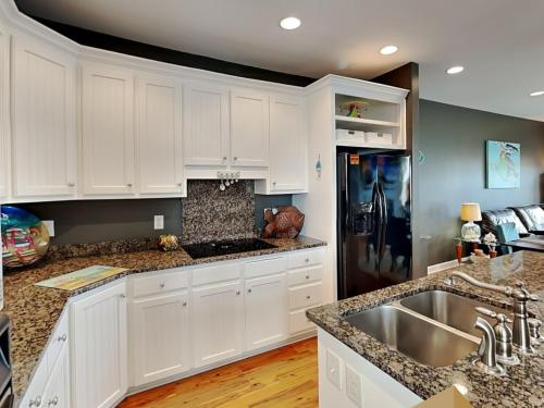 a kitchen with white cabinets and a black refrigerator at Lucky Ducky in Carolina Beach