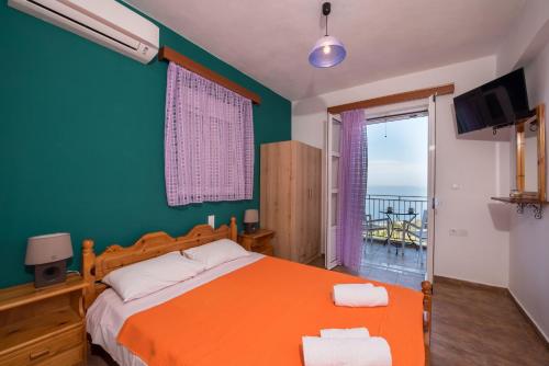 a bedroom with an orange bed and a balcony at Elena Studios in Athanion