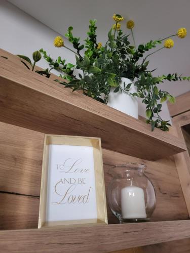 a candle and a book on a shelf with a sign at Regina S in Jagodina