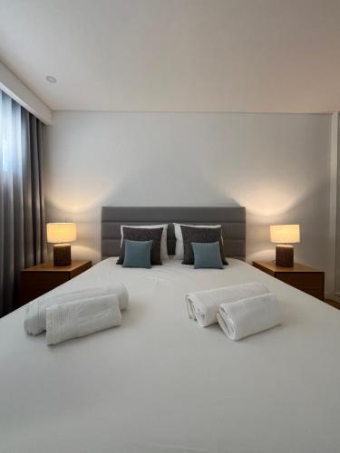 une chambre avec un grand lit blanc avec deux lampes dans l'établissement Sesimbra Blue Paradise, à Sesimbra