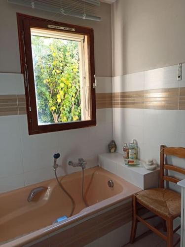 une salle de bain avec une baignoire et une fenêtre dans l'établissement Villa avec grand jardin au centre de St Florent, à Saint-Florent