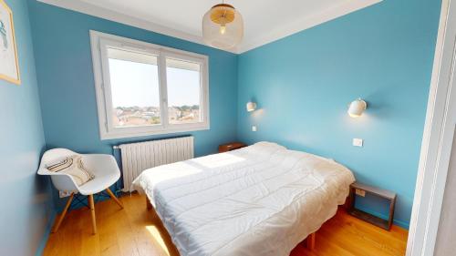 - une chambre bleue avec un lit et une chaise blanche dans l'établissement Le Refuge du Marin, à Saint-Gilles-Croix-de-Vie