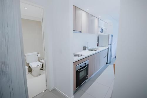 eine weiße Küche mit einem Waschbecken und einem WC in der Unterkunft Aunaisin- Austral - 306 - Vista increible in Ushuaia