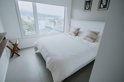 ein weißes Schlafzimmer mit einem großen weißen Bett und einem Fenster in der Unterkunft Aunaisin- Austral - 306 - Vista increible in Ushuaia