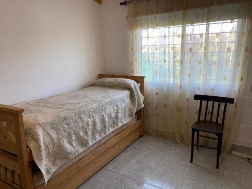 a bedroom with a bed and a chair and a window at El Quincho in San Miguel del Monte