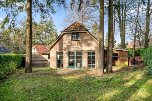 a house with a group of trees in the yard at Boshuis Veluwe in Lunteren