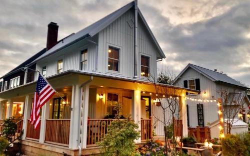una casa bianca con una bandiera americana sul portico di Cedarbrook Cottage by Seabrook Hospitality a Pacific Beach