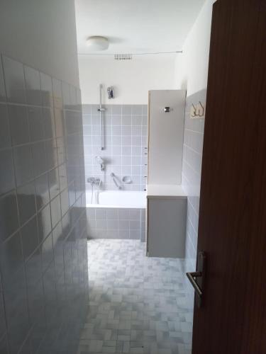 un bagno bianco con vasca e lavandino di Pension Trudering a Monaco