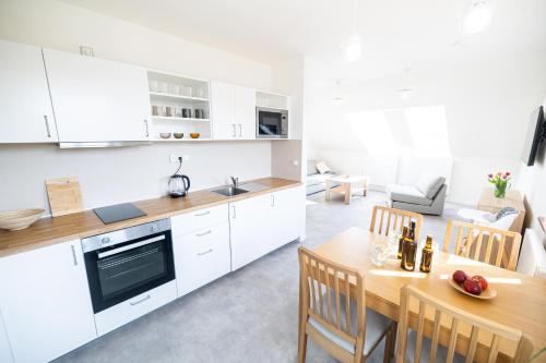 a kitchen and dining room with white cabinets and a table at Apartmány Bakovský pivovar in Bakov