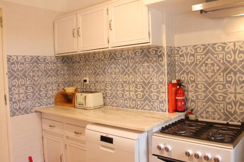 a kitchen with white cabinets and a stove top oven at Villa Alegria - A Private, Cozy Retreat in Nature in Lagos