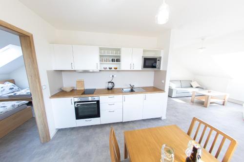 a kitchen with white cabinets and a table and a bed at Apartmány Bakovský pivovar in Bakov