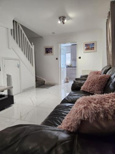 a living room with three black leather couches at Luxurious 2 Bedroom House With Garden And Free Parking in Thamesmead