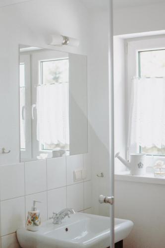 a white bathroom with a sink and a mirror at Folwark Stara Kuźnia in Miłki