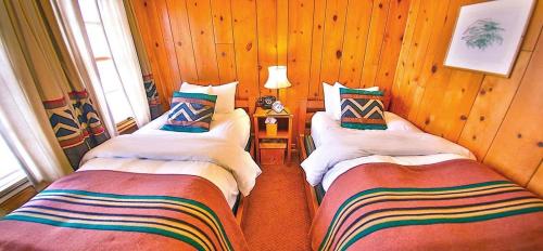 Habitación con 2 camas individuales y paredes de madera. en Timberline Lodge, en Government Camp