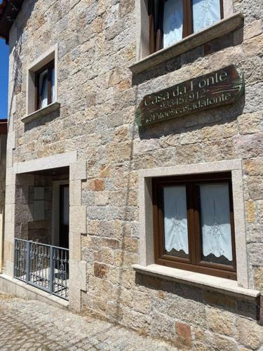 a stone building with windows and a sign on it at Casa da Fonte in Pitões das Júnias