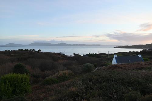 uma vista para o oceano a partir de uma colina com uma casa em Sea Breeze cottage at The Olde Forge B&B em Caherdaniel
