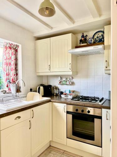 a kitchen with white cabinets and a stove top oven at Holly Cottage Cosy Home In Sherwood Forest in Edwinstowe