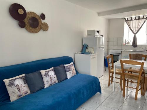 un salon avec un canapé bleu et une cuisine dans l'établissement Appartement 1 chambre et cuisine VIERVILLE-SUR-MER,plage du Débarquement, à Vierville-sur-Mer