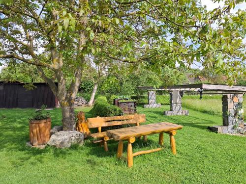 a wooden bench sitting under a tree in a yard at Apartmán Vysočina in Zvole