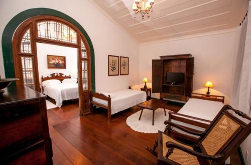 a large room with two beds and a tv at Pousada da Marquesa in Paraty