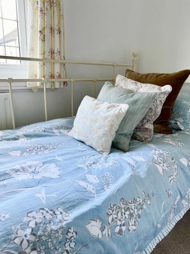 a bed with a blue comforter and two pillows at Holly Cottage Cosy Home In Sherwood Forest in Edwinstowe