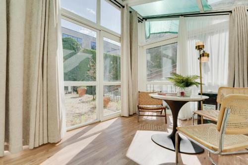 Atik Palace Hotel Vienna في فيينا: غرفة معيشة مع طاولة وكراسي ونوافذ كبيرة