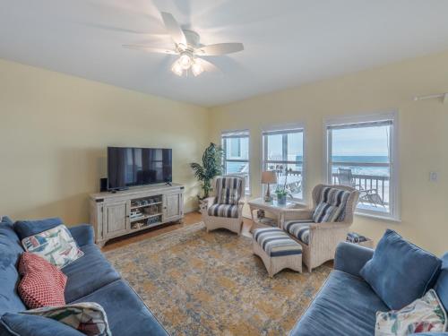 een woonkamer met een bank, stoelen en een tv bij Ocean Splendor in Surf City