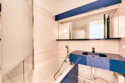 La salle de bains est pourvue d'un lavabo bleu et d'une baignoire. dans l'établissement Résidence Port du Crouesty - maeva Home - Appartement 2 pièces 4 personnes vue mer - Confort MAE-0611, à Arzon