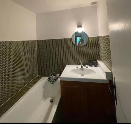 une salle de bain avec un lavabo, une baignoire et un miroir dans l'établissement Charmant gîte entre Caen et la mer, à Loucelles