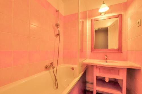 La salle de bains rose est pourvue d'un lavabo et d'une baignoire. dans l'établissement La résidence du Lac - maeva Home - Maison 3 pièces 6 personnes - Sélection MAE-9501, à Monflanquin