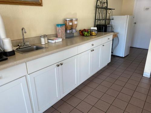 a kitchen with white cabinets and a sink and a refrigerator at Travel Inn - Lugoff in Lugoff