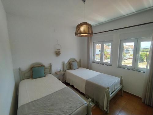 due letti in una stanza con due finestre di Casa Pereira a Vila Nova de Milfontes