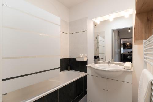 La salle de bains blanche est pourvue d'un lavabo et d'une baignoire. dans l'établissement Le Rubens - Appartement 2 chambres - 6 personnes - Parking - Métro, à Toulouse
