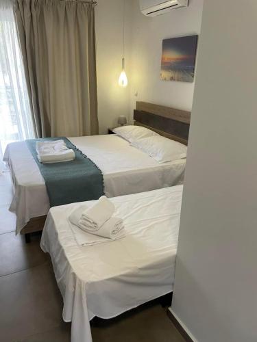 two beds in a hotel room with towels on them at Villa Alimos in Sarti