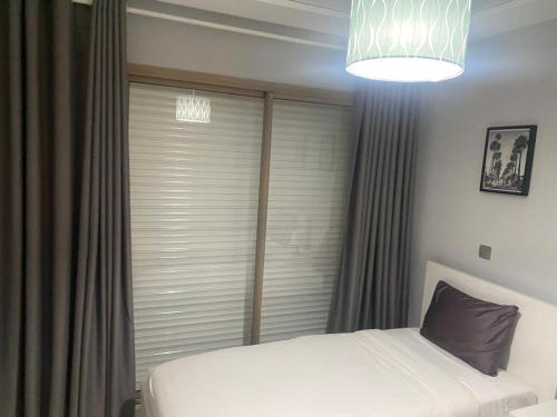 a bedroom with a white bed and a window at Marina Saidia Luxury Apartment with Pool & Garden View,Residence Tamaris in Saidia 