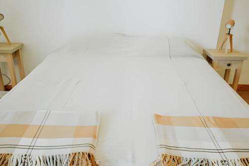 Una cama blanca con una manta. en Aunaisin-Paz Centro III en Ushuaia