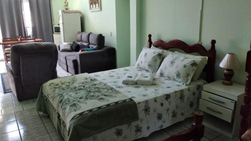 a bedroom with a large bed and a chair at POUSADA SERRANO in São Bento do Sapucaí