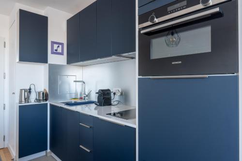 La cuisine est équipée de placards bleus et d'un réfrigérateur. dans l'établissement Elegant Flat with Terrace in the heart of Paris, à Paris